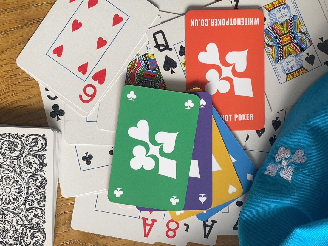 Colourful WHITE HOT playing cards arranged beside a blue poker cap