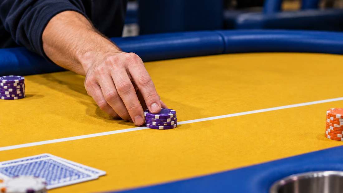 A hand moving purple poker chips across a white betting line on yellow cloth