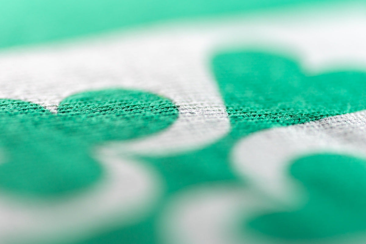 Macro detail of the white four-suit print on the green JOIN THE CLUB poker T-shirt